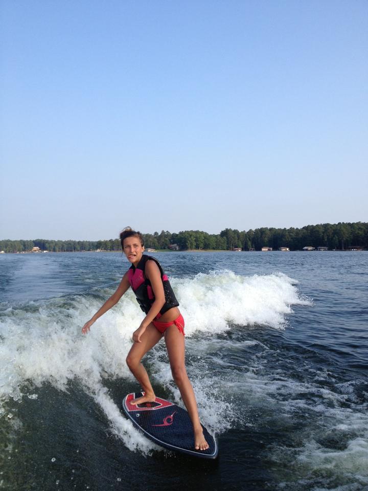 A Woman Rides a Wakesurf Board on a Wave