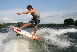 A Man Performs an Aerial Trick on a Wakesurf Board Above a Wave